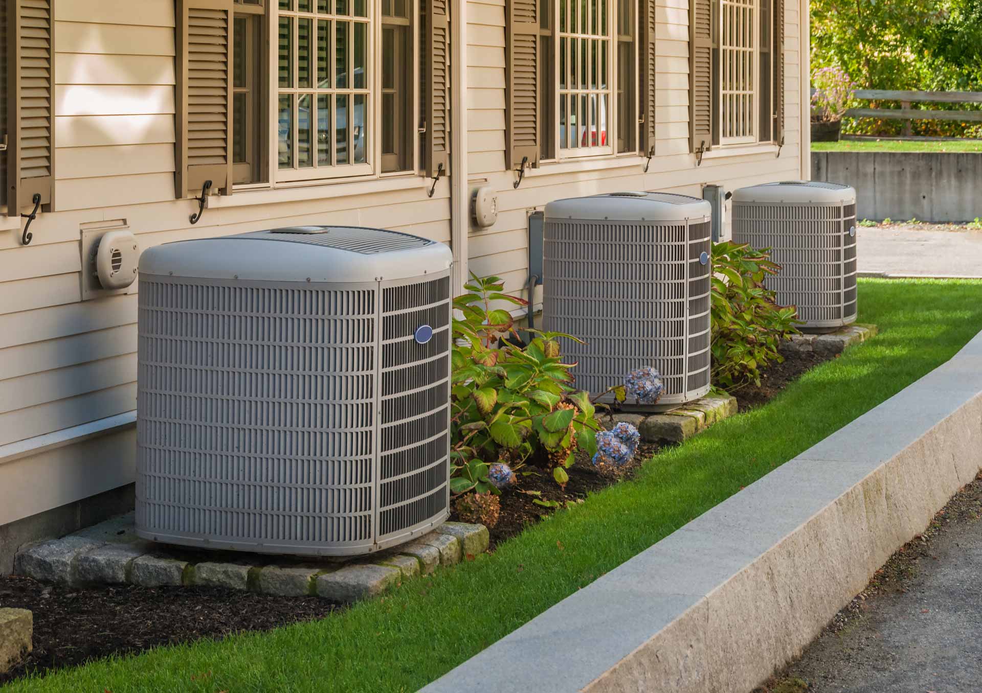 Three AC units in a flowerbed